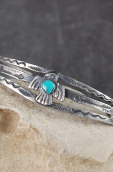 A silver bracelet with turquoise stone on top of it.
