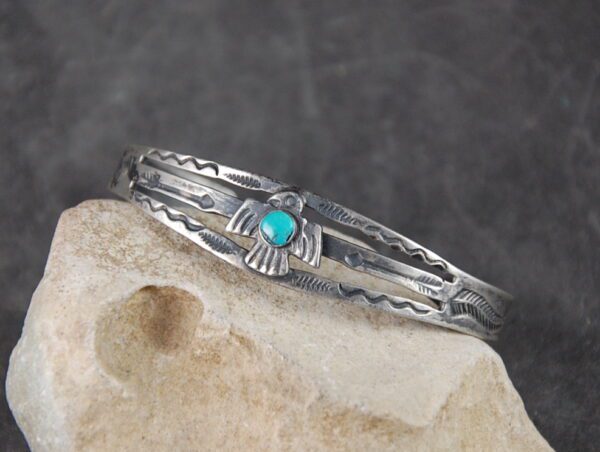 A silver bracelet with turquoise stone on top of it.