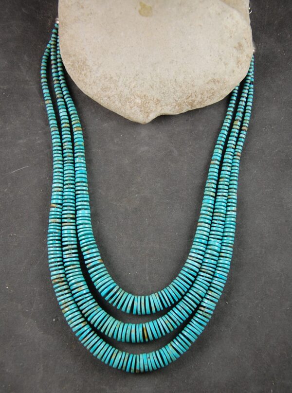 A necklace of three strands of turquoise beads.