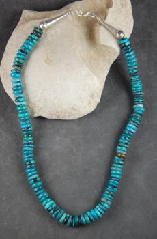 A necklace of turquoise beads is sitting on the beach.
