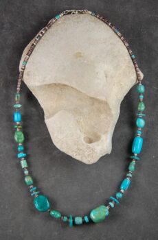 A necklace of turquoise and glass beads is displayed.