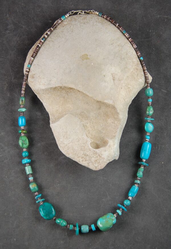 A necklace of turquoise and glass beads is displayed.
