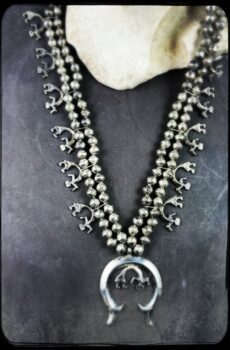 A necklace with a large silver pendant and small black beads.